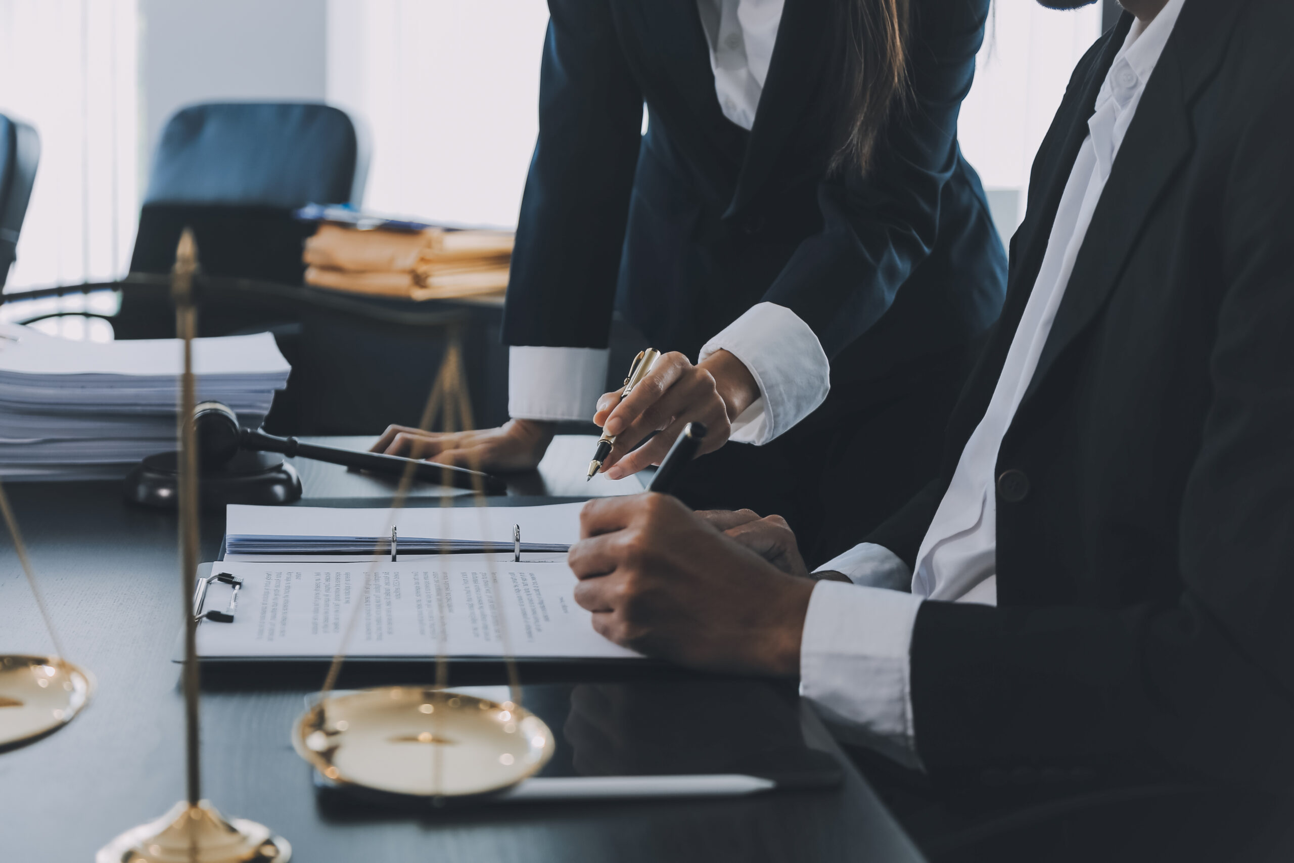 Business and lawyers discussing contract papers with brass scale